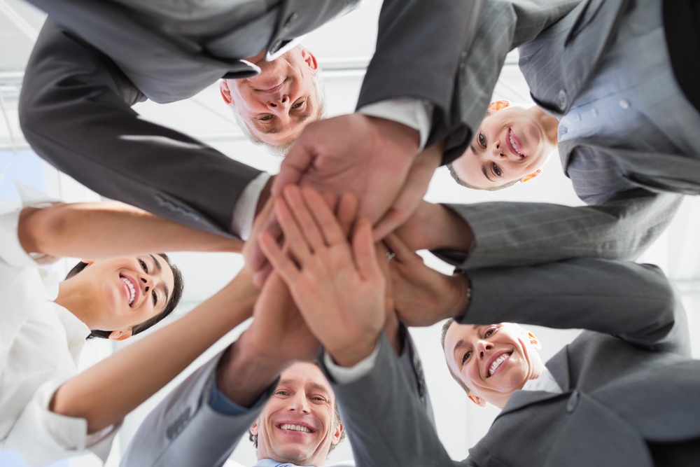 Business-team-standing-hands-together-in-the-office - How To Successfully Incorporate A New Member Into Your Team