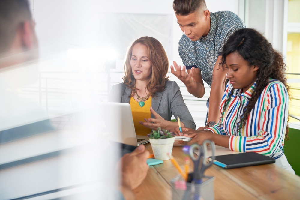 Multi-ethnic-group-of-succesful-creative-business-people-using-a-laptop-during-candid-meeting-1 - How to Unleash the Power of Diverse & Inclusive Teams